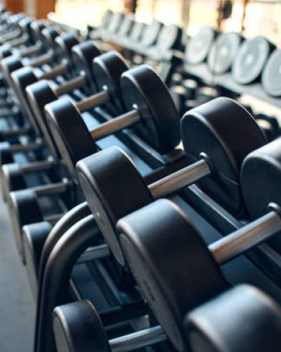 Sports equipment in the gym. Dumbbells of different weights on a shelf. Active healthy lifestyle and sports.